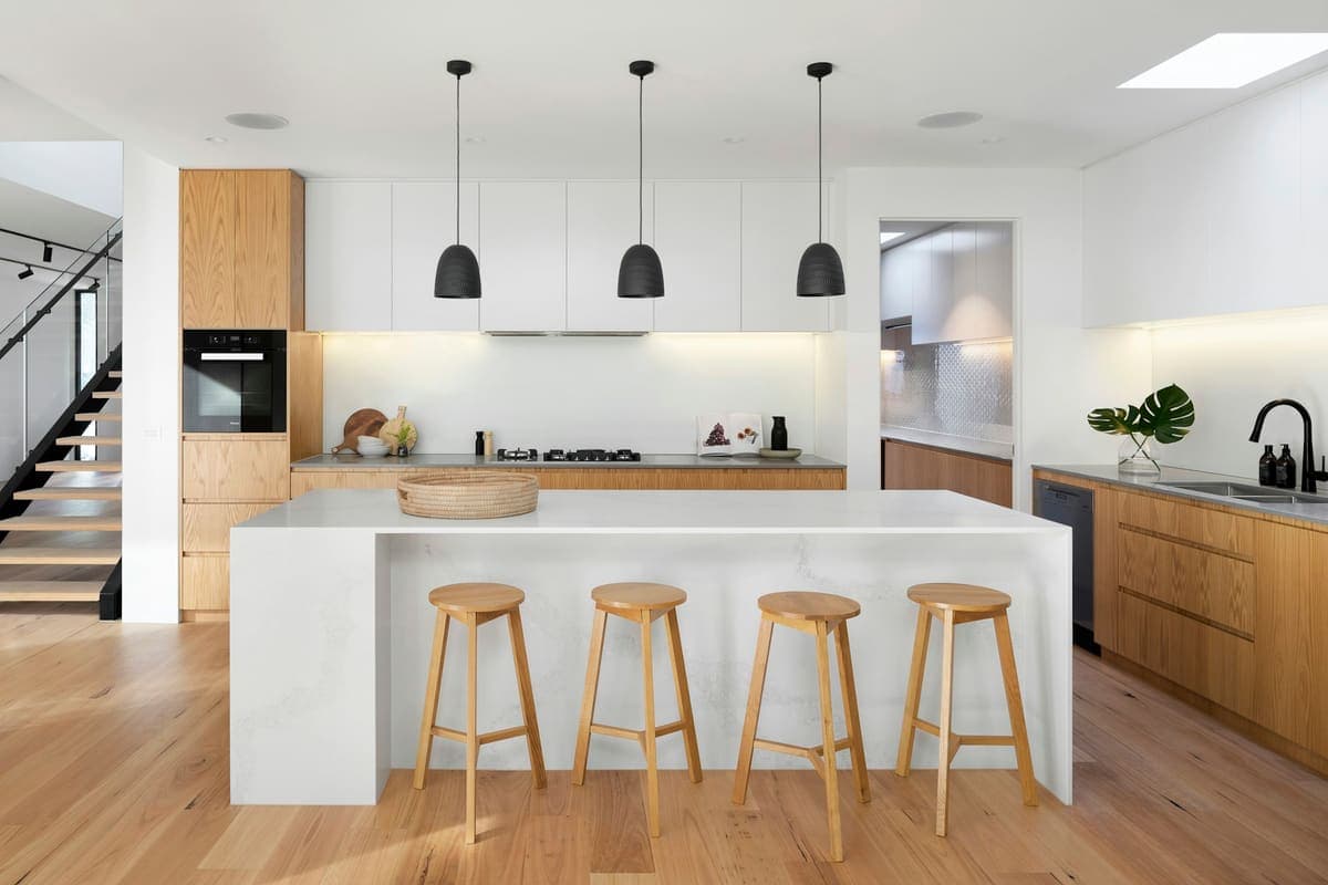 White kitchen with an island, stone counters and pendant lights