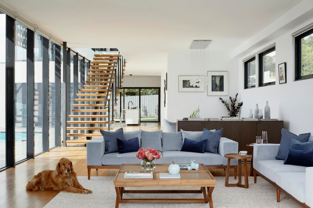 Bright living room with a gray sofa and an open staircase