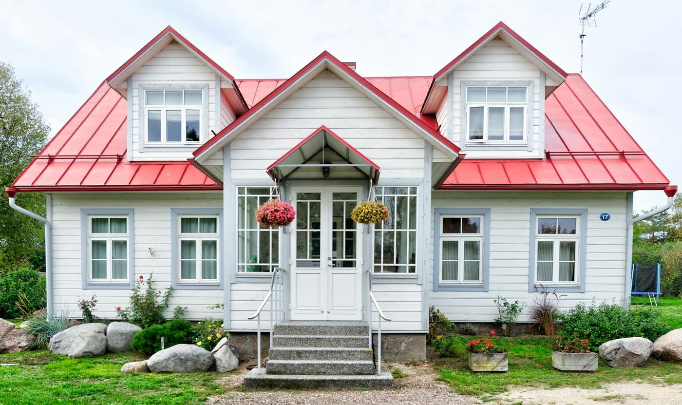 White cottage with a red metal roof